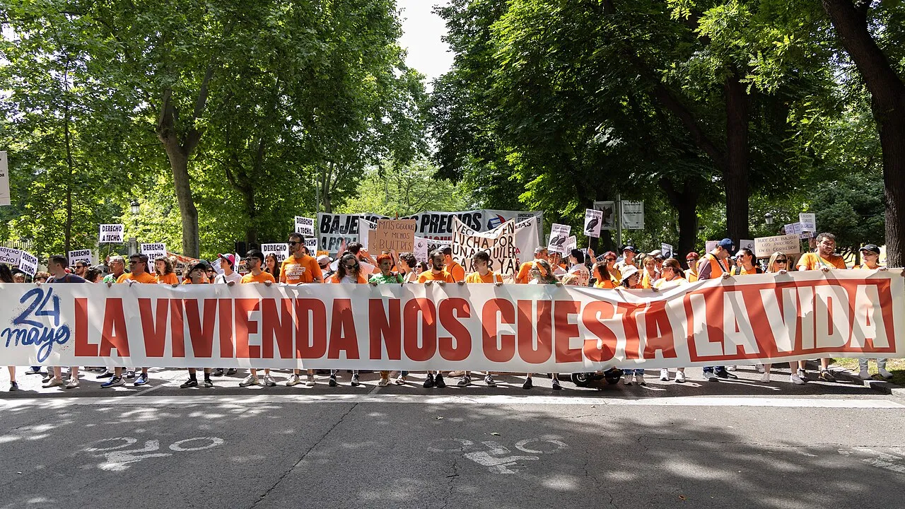 Demonstranten achter een spandoek met de tekst "Wonen kost ons het leven" tijdens een woonprotestmars in Madrid.